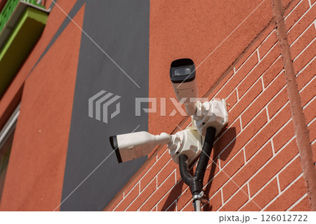 CCTV camera on the wall of a residential building for surveillance and protection in an urban area. CCTV camera on the wall of a residential building for surveillance and protection in an urban area. 126012722