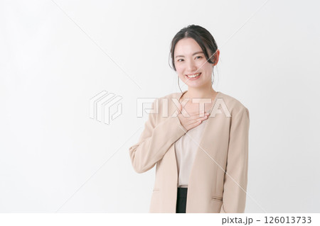 胸に手を当てるスーツ姿の20代女性 胸に手を当てるスーツ姿の20代女性 126013733