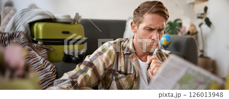 Man with confused face reads the map, traveller plans holiday, looks puzzled Man with confused face reads the map, traveller plans holiday, looks puzzled 126013948