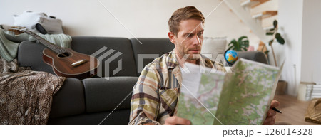 Portrait of man, traveller looks confused at map, studying the route to go on vacation or business trip Portrait of man, traveller looks confused at map, studying the route to go on vacation or business trip 126014328