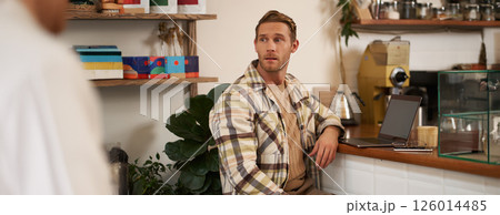 Small business concept. Handsome businessman, cafe owner, sitting near counter with laptop and smartphone, working in coffee shop 126014485
