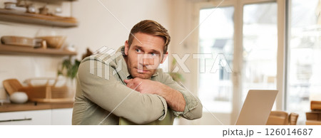 Vertical portrait of handsome masculine man, sitting on chair, looking aside, waiting for an order in coffee shop Vertical portrait of handsome masculine man, sitting on chair, looking aside, waiting for an order in coffee shop 126014687