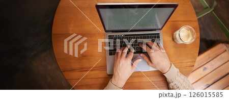 Close up portrait of male hands typing on keyboard, working on laptop in cafe, computer and cappuccino standing on wooden table in coworking space Close up portrait of male hands typing on keyboard, working on laptop in cafe, computer and cappuccino standing on wooden table in coworking space 126015585