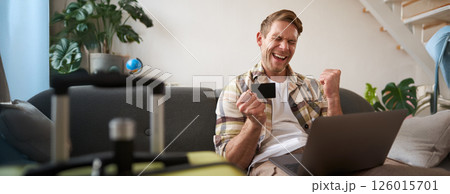 Portrait of man going on vacation, looking at his credit card, buying tickets online, booking hotel on website, preparing for holiday Portrait of man going on vacation, looking at his credit card, buying tickets online, booking hotel on website, preparing for holiday 126015701