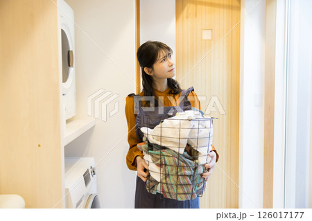 ドラム式洗濯機から洗濯物を取り出す女性 ドラム式洗濯機から洗濯物を取り出す女性 126017177