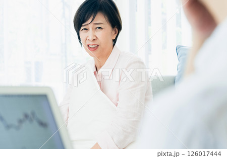 リビングでパソコンを見てショックを受ける中高年夫婦 126017444