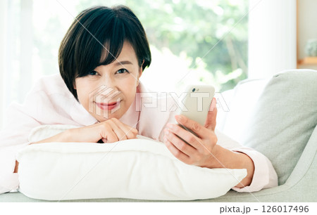 ソファでスマホを見るミドル女性 126017496