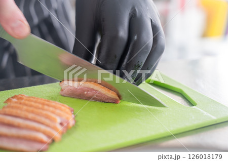 The chef slices the roast duck. The chef slices the roast duck. 126018179