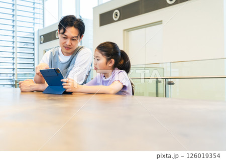タブレットを見る女の子と使い方を教える男性 タブレットを見る女の子と使い方を教える男性 126019354