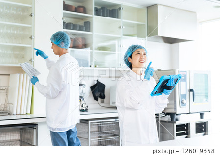 厨房をチェックする衛生白衣を着た男女作業員 126019358