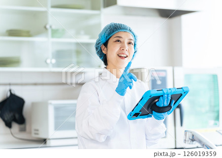 キッチンをチェックする衛生白衣を着た女性作業員 126019359
