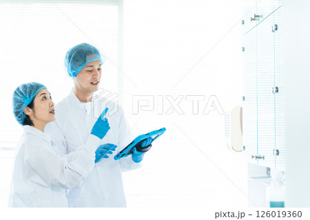 倉庫をチェックする衛生白衣を着た男女作業員 126019360
