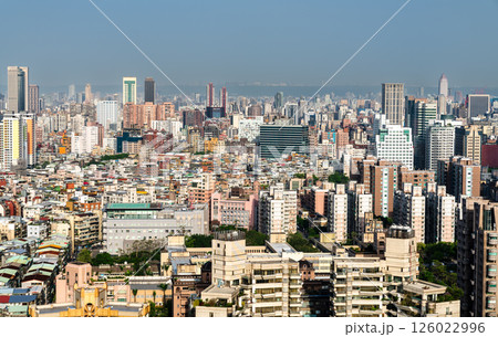 A sprawling urban landscape of Taipei, Taiwan, filled with densely packed residential and commercial buildings, high-rises, and towers stretching toward the horizon under a bright, clear sky. 126022996