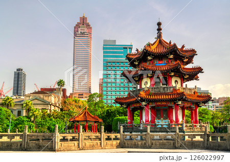 A traditional Chinese pavilion in 228 Peace Memorial Park, Taipei, Taiwan, stands elegantly before a backdrop of modern skyscrapers, reflecting the contrast between cultural heritage and urban 126022997