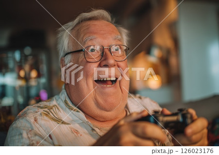 close up of senior verweighted man reacting excitedly to what is happening on the screen. playing game on console close up of senior verweighted man reacting excitedly to what is happening on the screen. playing game on console 126023176