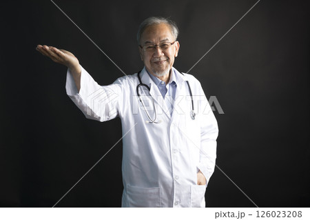 Asian doctor with stethoscope around his neck with thumb up hand stand on black background. Asian doctor with stethoscope around his neck with thumb up hand stand on black background. 126023208