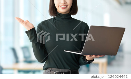 パソコンを持って案内をする笑顔の女性・ビジネスウーマン パソコンを持って案内をする笑顔の女性・ビジネスウーマン 126024441