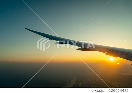 Airplane wing above Osaka coast during sunset descent flight 126024483