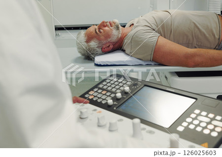 Male patient undergoing X-ray examination using tilting radiographic wall stand. Male patient undergoing X-ray examination using tilting radiographic wall stand. 126025603