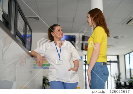 Nurse talking with teenage patient in hospital waiting room. 126025657