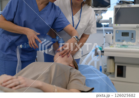 Medical staff applying oxygen mask to unconscious teenage girl in hospital. 126025682