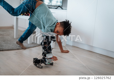 Boy having fun with small robot at home as part of STEM learning. 126025762