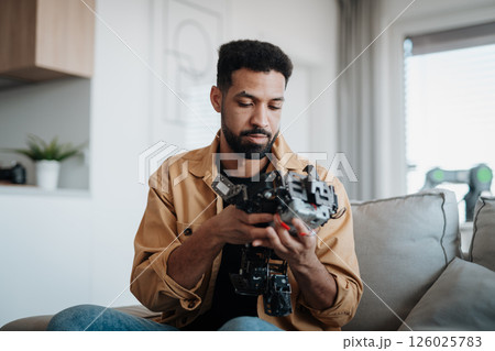 Handsome engineer student working on robot project at home. Handsome engineer student working on robot project at home. 126025783