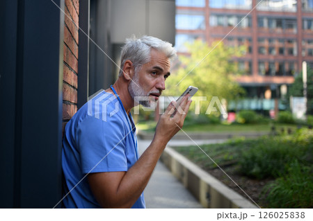 Doctor recording a voice message to his family saying he has to stay late at work. Doctor recording a voice message to his family saying he has to stay late at work. 126025838