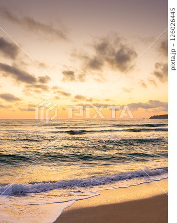 sea tide on the beach in summer. orange glow on the sky with clouds at dawn. beautiful nature condition before sunrise. dramatic weather at golden hour. zen velvet season vacation 126026445
