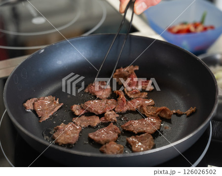 The chef fries veal in a frying pan. The chef fries veal in a frying pan. 126026502