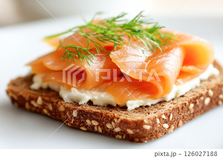 Delicious open-faced sandwich featuring smoked salmon layered on whole grain bread with creamy spread and fresh herbs, perfect for gourmet breakfast or brunch 126027188