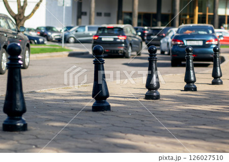 There is a striking row of black chess pieces displayed on the sidewalk There is a striking row of black chess pieces displayed on the sidewalk 126027510