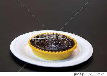 There is a white plate featuring a delicious chocolate tart on it 126027523