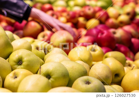 A person is currently picking fresh apples from a large pile of apples A person is currently picking fresh apples from a large pile of apples 126027530