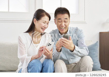 スマートフォンを使うシニアの夫婦 リビング スマートフォンを使うシニアの夫婦 リビング 126028245