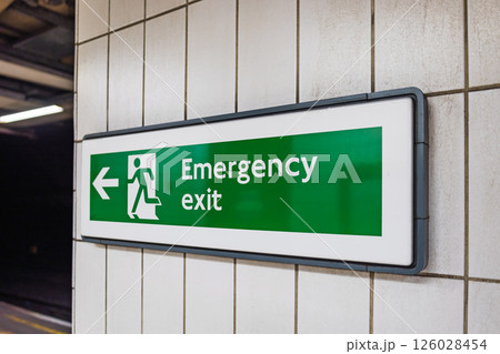 Green Emergency Exit Sign in Underground Subway Station with Directional Arrow 126028454