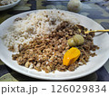 Traditional Gambian Nyebbeh Meal with Rice, Black-Eyed Peas, and Scotch Bonnet Pepper on White Plate 126029834