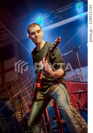Musician plays a guitar on stage... Musician plays a guitar on stage... 126031182