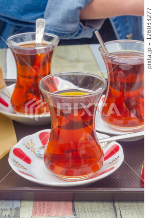 Traditional Turkish tea in tulip glasses served with spoons on white saucers. High quality photo 126033277