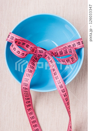 Measuring tape around empty bowl on table Measuring tape around empty bowl on table 126033347