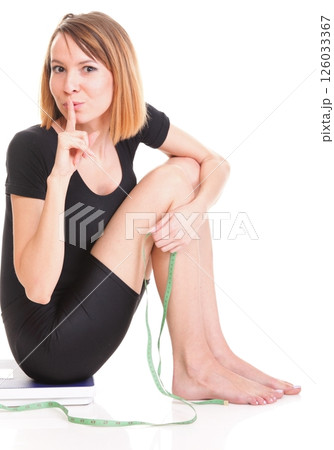 Portrait of a happy woman squatting on scales isolated 126033367