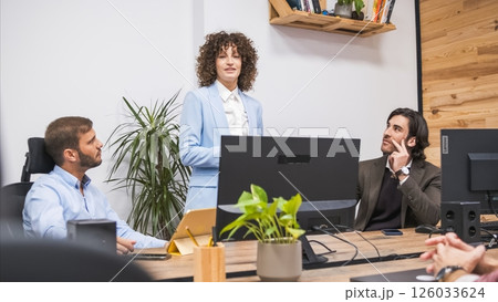 Confident businesswoman explaining strategy to male colleagues in office Confident businesswoman explaining strategy to male colleagues in office 126033624
