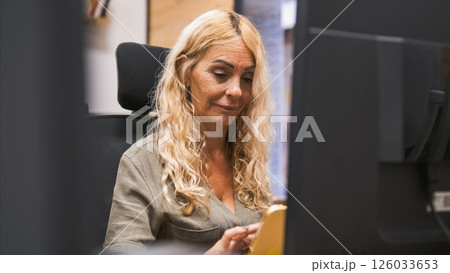 Smiling blond businesswoman using tablet computer in office Smiling blond businesswoman using tablet computer in office 126033653