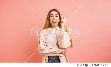 Young woman having an idea pointing upwards on pink background 126033739