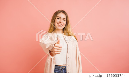 Young woman showing thumbs up sign on pink background 126033744