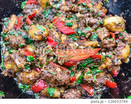 Spicy beef stir-fry with peppers and potatoes prepared outdoors during a sunny day Spicy beef stir-fry with peppers and potatoes prepared outdoors during a sunny day 126033784