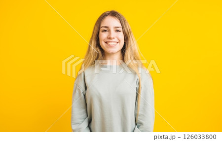 Young woman smiling on yellow background: casual portrait of cheerful female 126033800