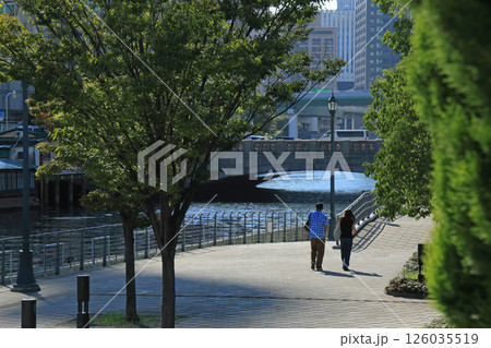 緑豊かな大阪、中之島公園をなにわ橋に向かって歩く二人の男女 緑豊かな大阪、中之島公園をなにわ橋に向かって歩く二人の男女 126035519