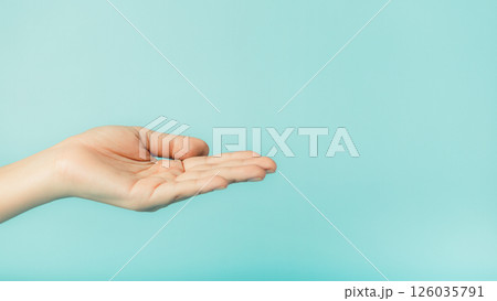 Close up of female hand holding something on blue background with copy space 126035791