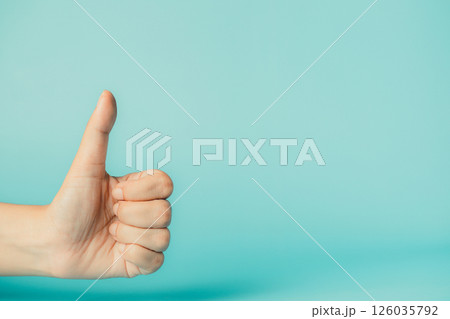Female hand showing thumbs up sign on blue background with copy space. 126035792